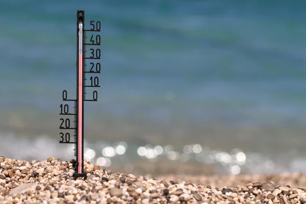 Thermometer on a beach shows high temperatures — Stock Photo, Image