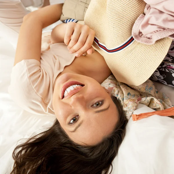 Schöne junge schlanke Frau auf dem Bett drinnen Auspacken von Kleidung — Stockfoto