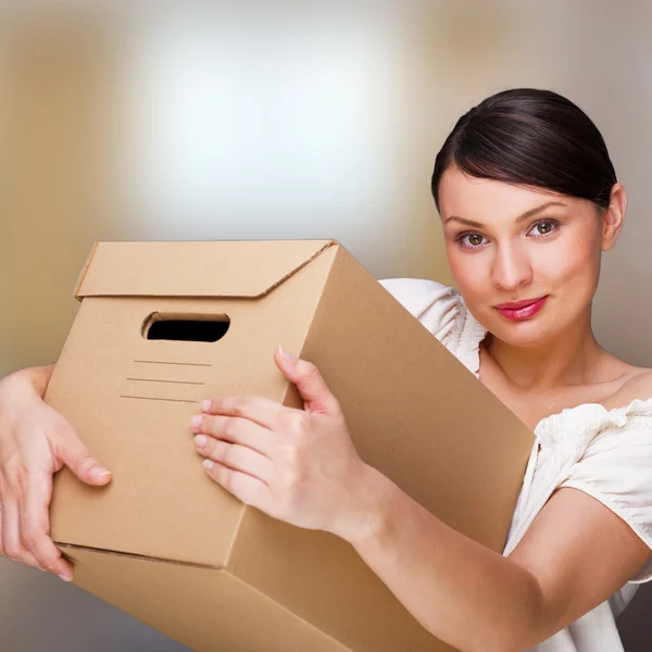 Усміхнена жінка вдома тримає коробки. Вона рухається до неї — стокове фото