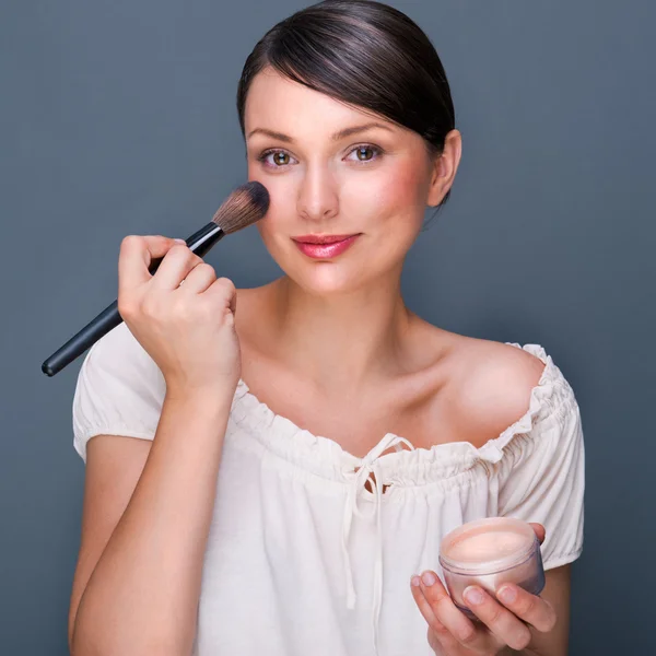 Retrato de uma mulher bonita com pincel de maquiagem perto de seu rosto lo — Fotografia de Stock