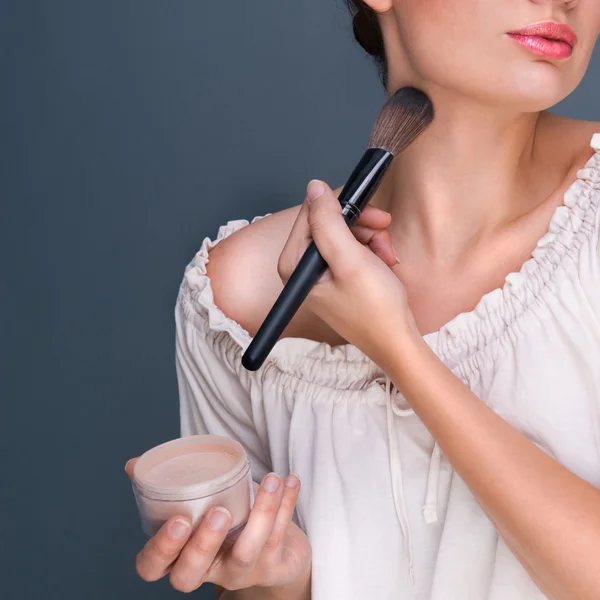 Portret van een mooie vrouw met make-up borstel in de buurt van haar gezicht lo — Stockfoto