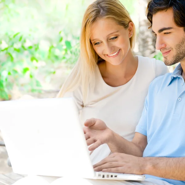 Jovem casal trabalhando no laptop e sorrindo enquanto sentado relaxado — Fotografia de Stock