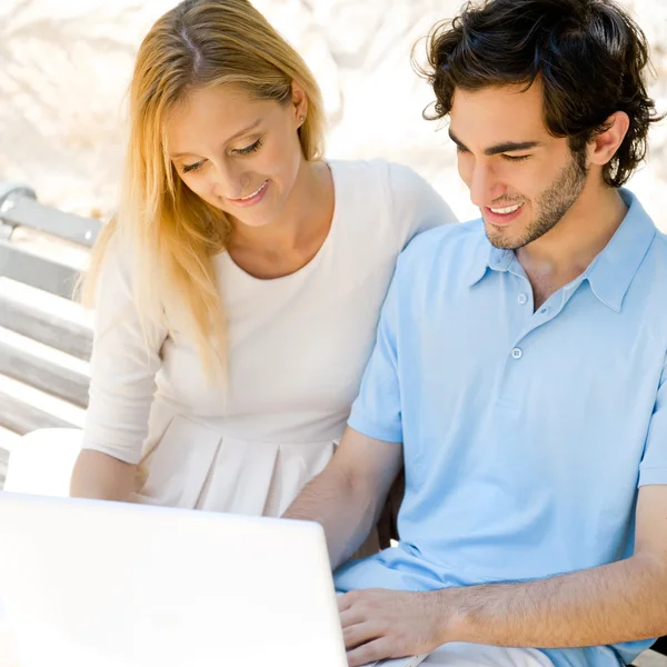 Mladý pár, pracovat na notebooku a usmíval se při sezení se uvolnil — Stock fotografie