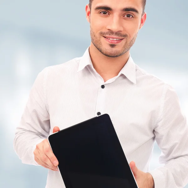 Человек, показывающий экран планшетного компьютера, улыбающийся стоя перед своим офисом — стоковое фото
