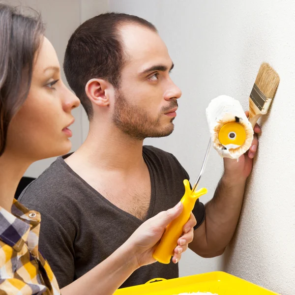 Happy smiling couple painting interior wall of home and having f — Stock Photo, Image