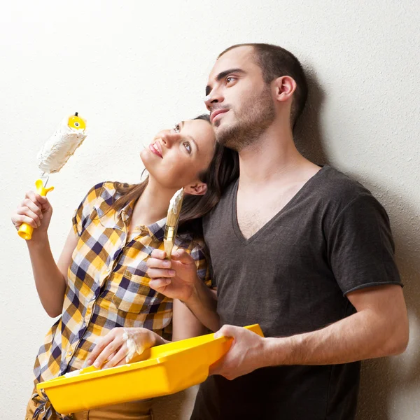 Feliz casal sorrindo pintura parede interior de casa e ter f — Fotografia de Stock