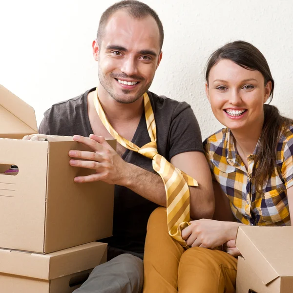 Casal jovem com caixas no novo apartamento sentado no chão um — Fotografia de Stock