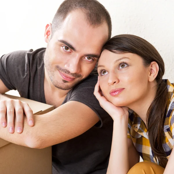 Mladý pár s boxy v novém bytě, sedí na podlaze — Stock fotografie
