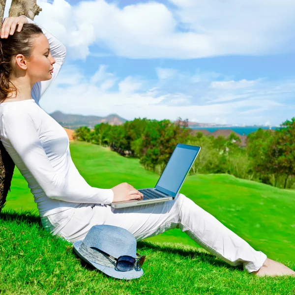 Hezká žena sedí stromu s přenosným počítačem — Stock fotografie