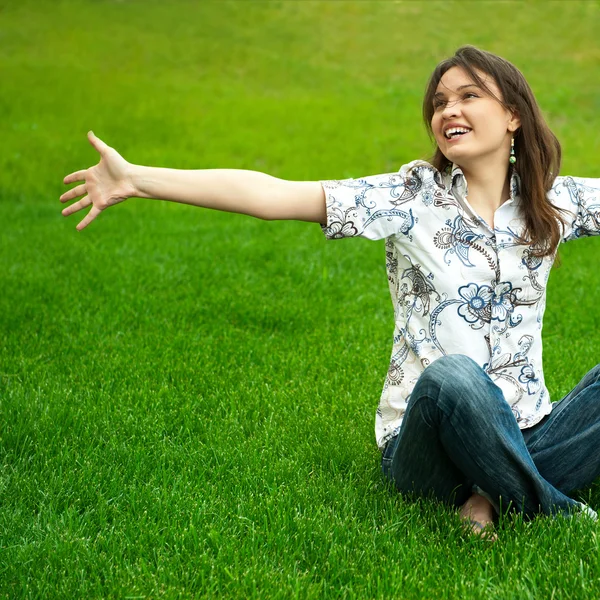 Volle Länge der hübschen jungen Frau, die auf Gras ruht und lächelt. — Stockfoto