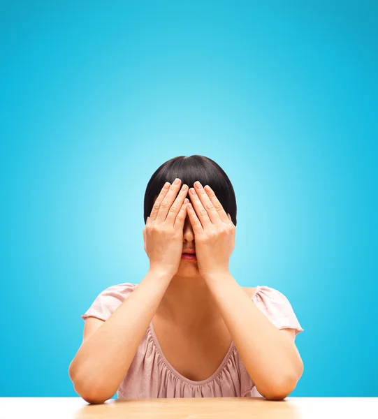Ung kvinna sitter isolerad mot blå bakgrund med ögon c — Stockfoto