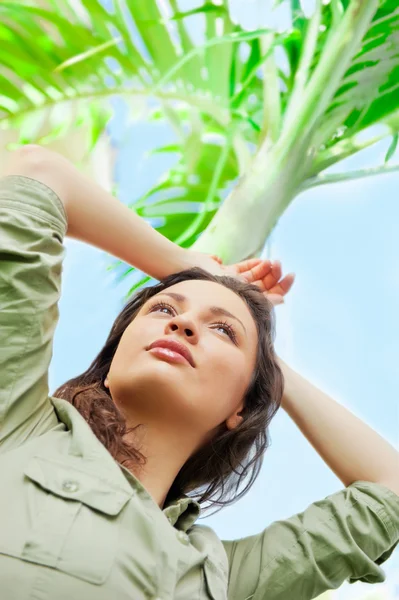 Porträtt av unga vackra kvinnan lutar sig på Palm och njuter — Stockfoto