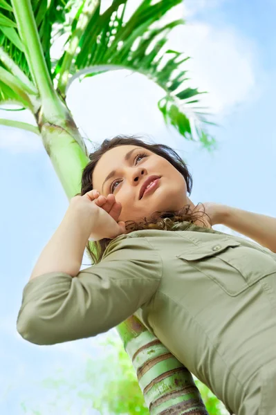 年轻漂亮的女人靠在棕榈树上，享受的肖像 — 图库照片