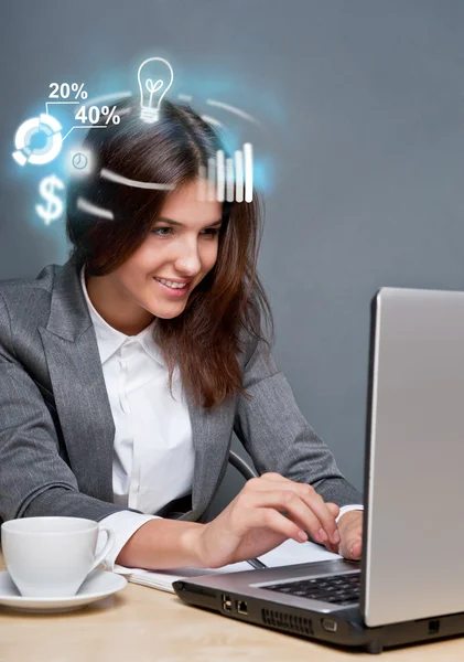 Jeune femme d'affaires travaillant sur son ordinateur portable et icônes avec diffèrent — Photo