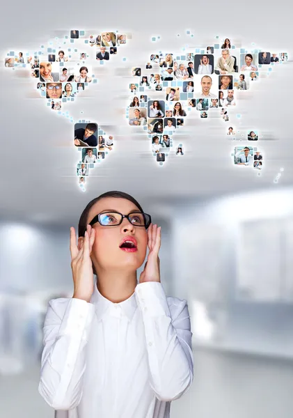 Portrait of young woman communicating with her friends across the world. Standing against world map with photo of . International communications concept — Stock Photo, Image