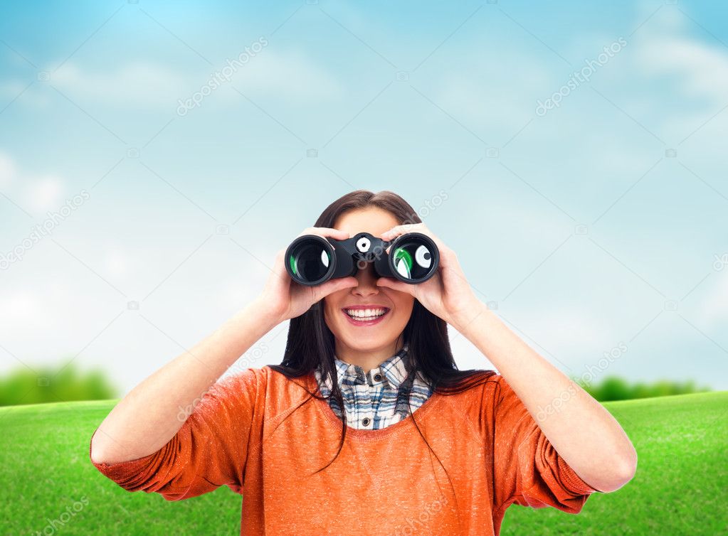 Woman looking through binoculars at summer park