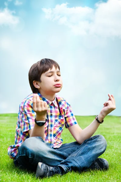 Photo of adorable young wise boy sitting on the grass at his bac — Stock Photo, Image