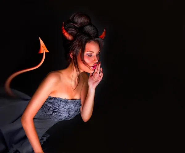 Сексуальная дьяволица с хвостовыми рогами и красной кожей шепчущая что-то — стоковое фото