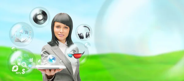Pretty business woman holding tablet computer and different objects are flying from touch screen — Stock Photo, Image