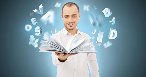 Adult man holding an opened book and reading. Letters are flying — Stock Photo, Image
