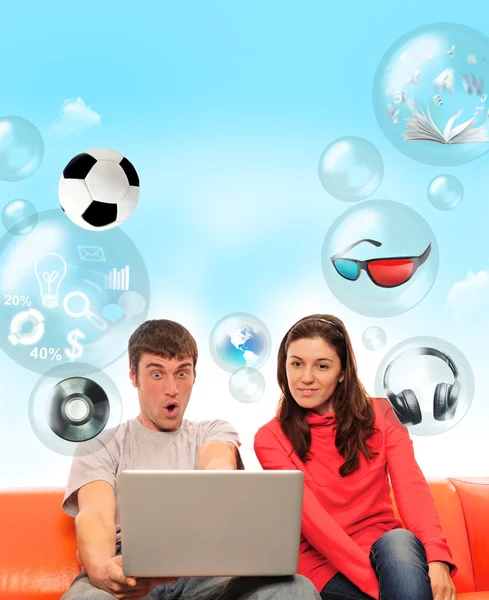 Adulto casal sentado no sofá e se divertindo usando seu laptop . — Fotografia de Stock