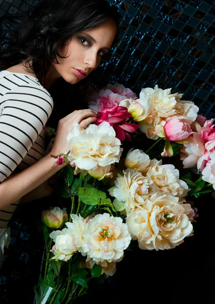 Virágok a sötét szobában a gyönyörű fiatal nő portréja — Stock Fotó