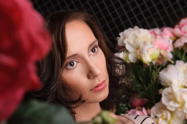 Virágok a sötét szobában a gyönyörű fiatal nő portréja — Stock Fotó