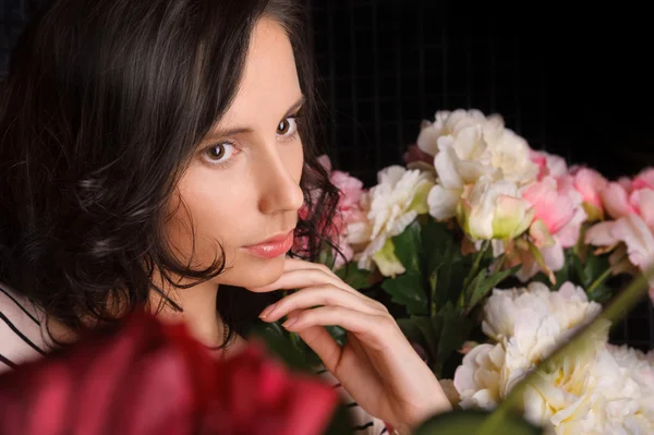Retrato de jovem mulher linda com flores no quarto escuro com — Fotografia de Stock