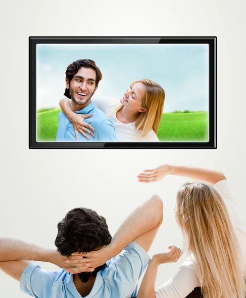 Fiatal pár néz-uk fénykép a széles képernyős tv otthon — Stock Fotó