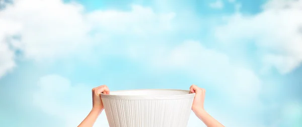 Mãos femininas segurando cesta vazia contra belo céu — Fotografia de Stock