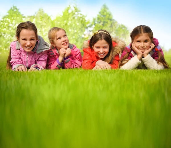 Happy group of girls lying on a green grass — Stock Photo, Image