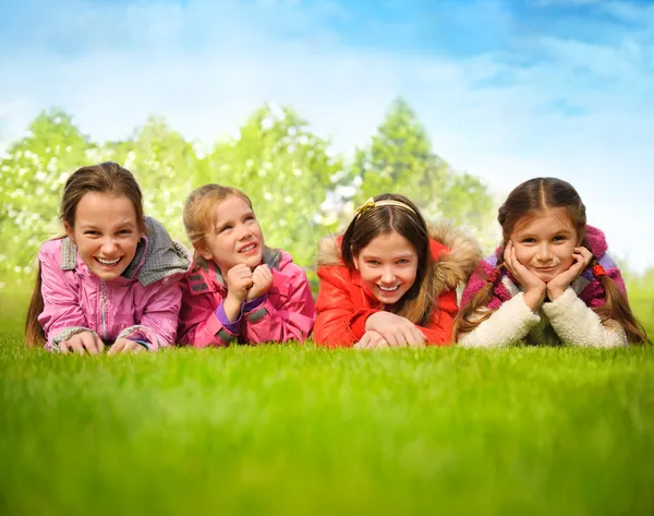 Glückliche Gruppe von Mädchen, die auf einem grünen Gras liegen — Stockfoto