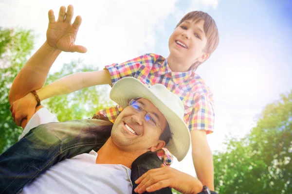 Portrait of smiling father giving his son piggyback ride outdoor — Stock Photo, Image
