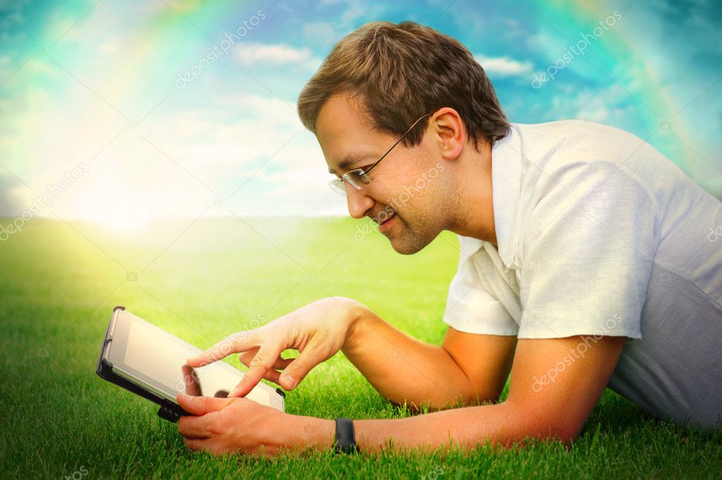 Adult man at summer park resting on weekend using his tablet com