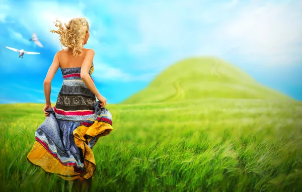 Young woman running across field. Photo from behind — Stock Photo, Image