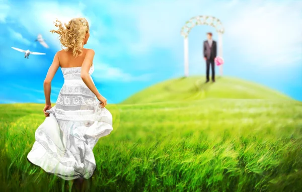 Jeune mariée courant vers son marié pour autel à travers la prairie — Photo
