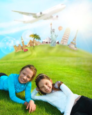 Two young girls laying on a grass against world's famous buildin clipart