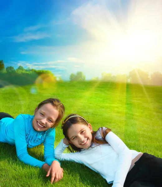 Two little sisters are resting on grass against idyllic landscap — Stock Photo, Image