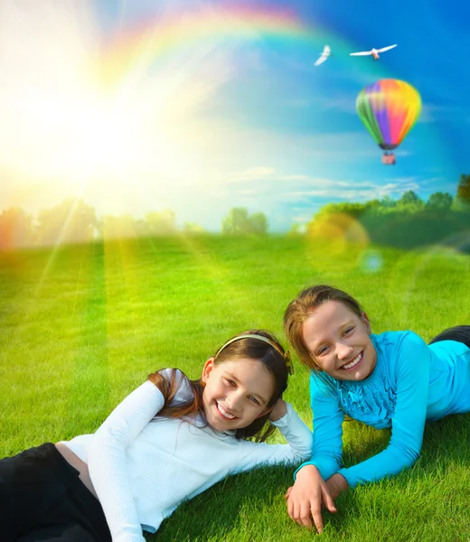 Две младшие сестры отдыхают на траве против идиллического ландшафта — стоковое фото