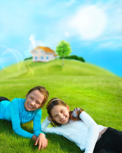 Two young girls laying down on grass and smiling. Beautiful hous — Stock Photo, Image