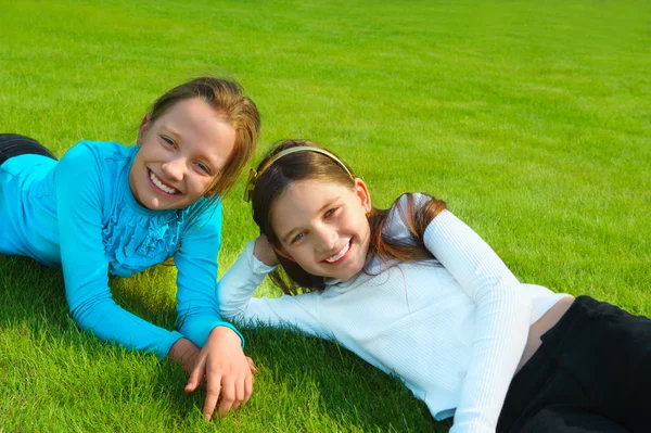 Two sisters laughing and playing in the park, laying down. — Stock Photo, Image