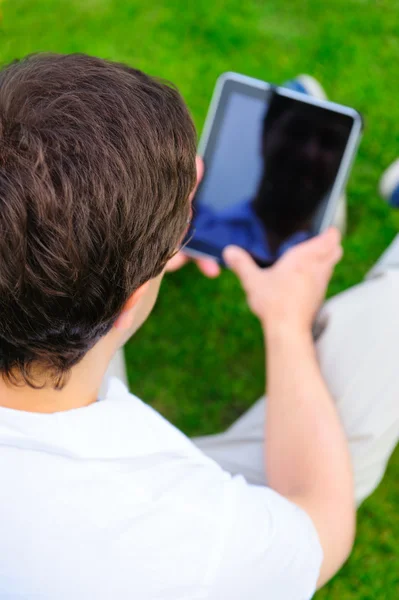 Vuxen man arbetar med tablet PC utomhus i parken — Stockfoto