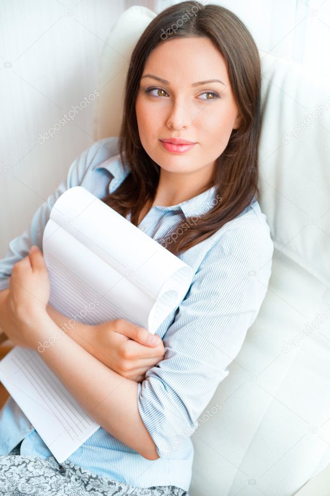 Portrait of a sensual young woman reading a novel while sitting