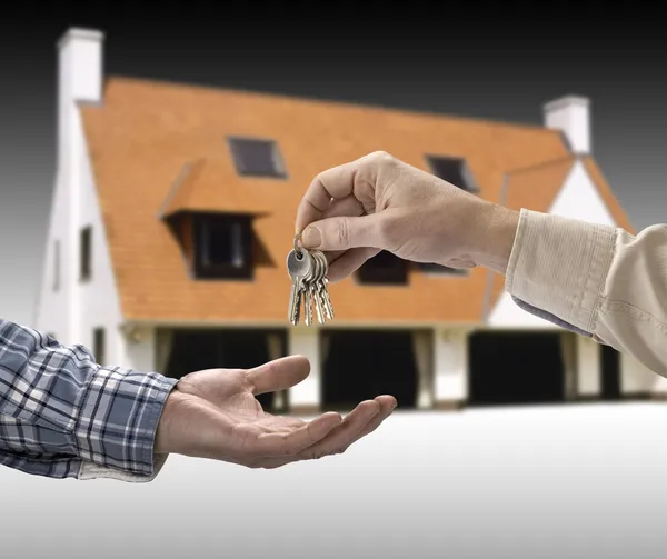 El hombre está entregando una llave de la casa a otro hombre en la forma de la ho — Foto de Stock