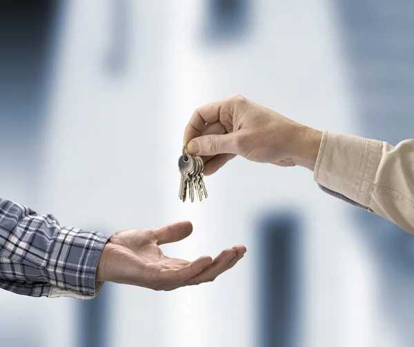 El hombre está entregando una llave de la casa a otro hombre en la forma de la ho — Foto de Stock
