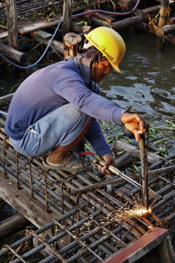 Thailand, Bangkok, a thai welder working at the contruction of a bridge on the Chao Phraya river clipart