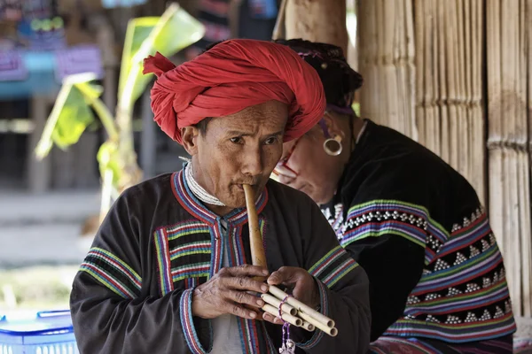 Tailandia, Chiang Mai, Karen Long Neck aldea de la tribu de la colina (Kayan Lahwi), Karen hombre en trajes tradicionales tocando una flauta — Foto de Stock
