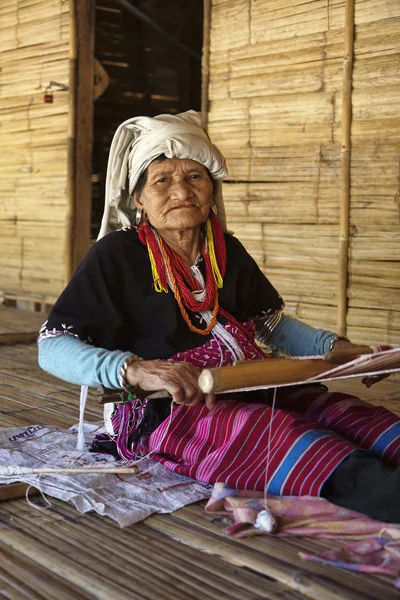 Thailand, Chiang Mai, Karen Long Neck hill tribe village (Kayan Lahwi), a Karen woman in traditional costumes is making a carpet — Stock Photo, Image