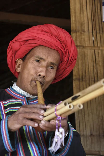 Таиланд, Чиангмай, деревня племени Карен Лонг Нек (Каян Лахви), мужчина Карен в традиционных костюмах, играющий на флейте — стоковое фото