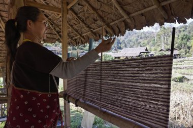 Tayland, chiang mai, karen uzun boyunlu tepe kabile Köyü (kayan lahwi), karen kadın geleneksel kostümleri bir halı yapıyor